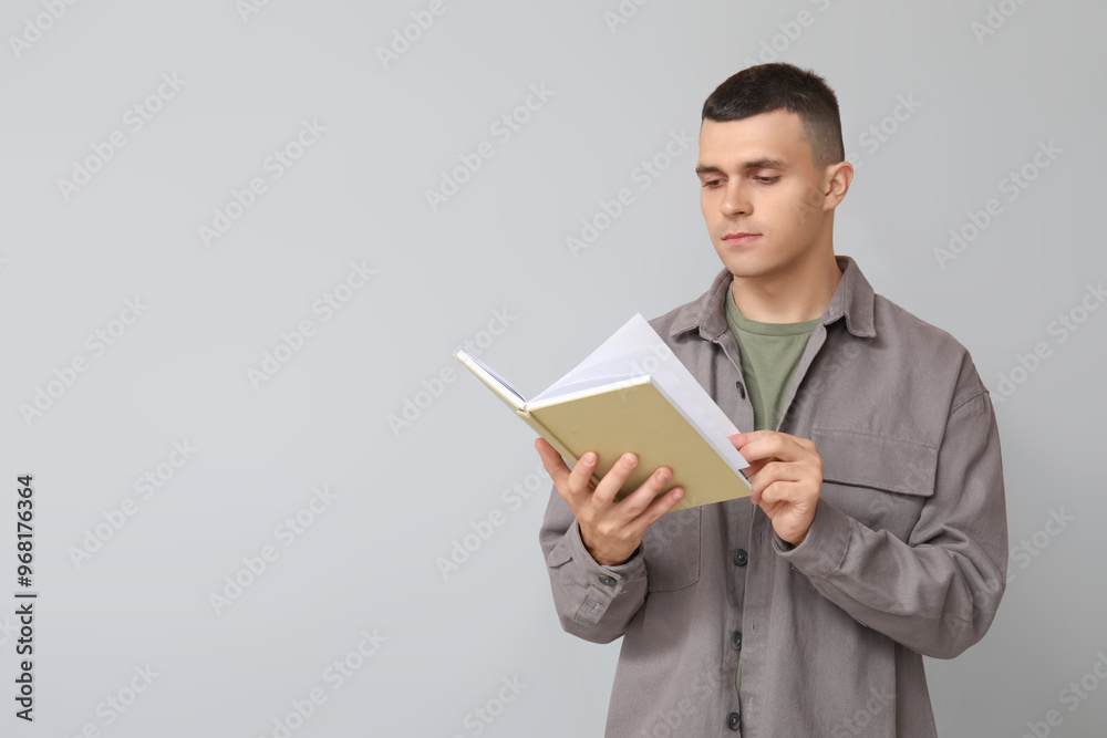 Handsome young man reading book on grey background Handsome young man reading book on grey background