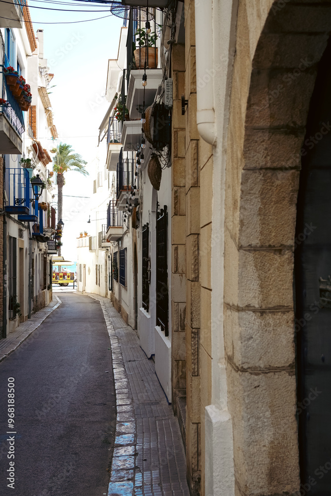 A narrow street with a view of the sea in Sitges, a beautiful resort village in Catalonia, Spain A narrow street with a view of the sea in Sitges, a beautiful resort village in Catalonia, Spain