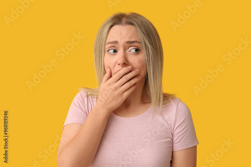 Embarrassed young woman on yellow background