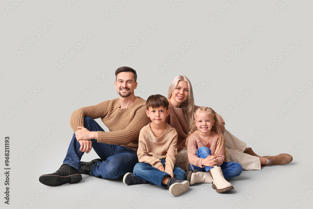Happy family with children in winter clothes sitting on grey background Happy family with children in winter clothes sitting on grey background