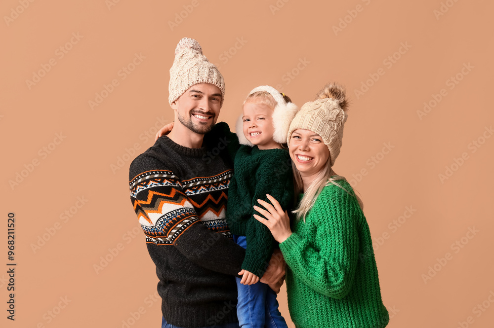 Happy couple with daughter in winter clothes on beige background
