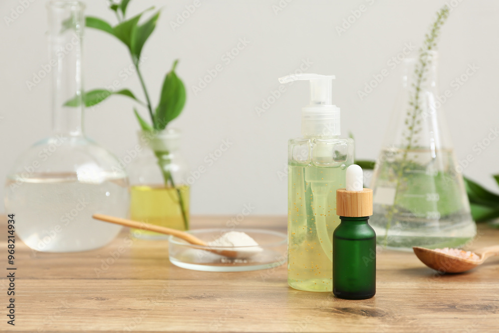 Laboratory glassware with ingredients and samples for preparing natural cosmetics on brown wooden table near white wall Laboratory glassware with ingredients and samples for preparing natural cosmetics on brown wooden table near white wall