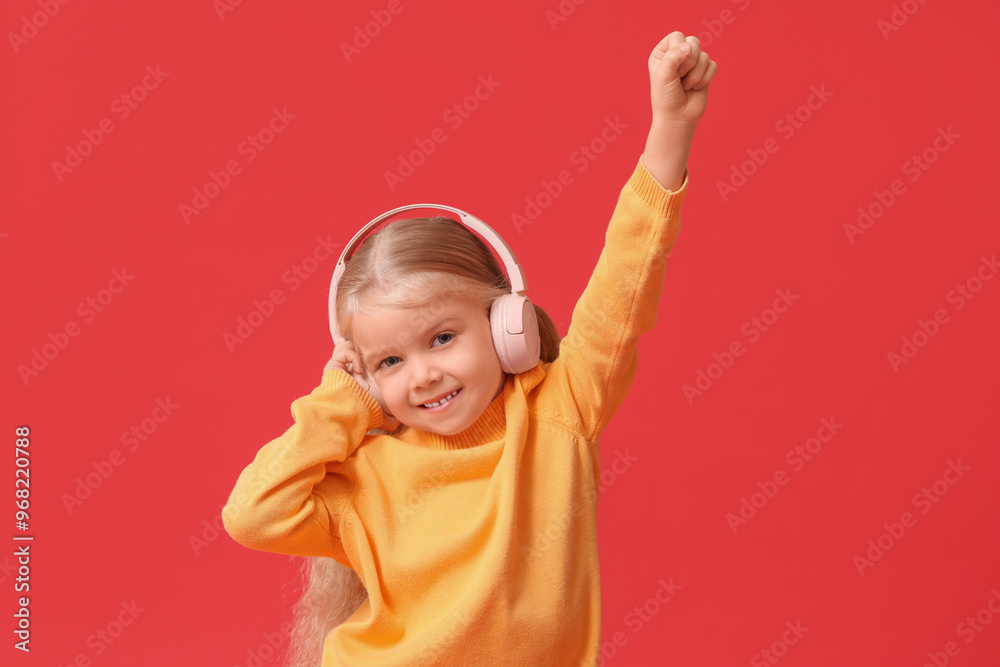 Cute little happy girl in warm stylish sweater and headphones on red background Cute little happy girl in warm stylish sweater and headphones on red background