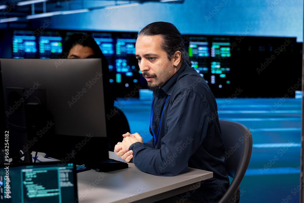 Computer scientists in data center updating systems, protecting servers from damaging software vulnerabilities. Coworkers looking for errors causing infrastructure to slow down Computer scientists in data center updating systems, protecting servers from damaging software vulnerabilities. Coworkers looking for errors causing infrastructure to slow down