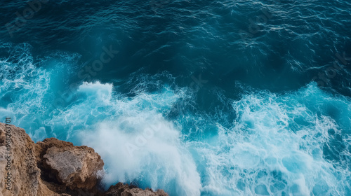 Ocean waves crashing onto rocky cliffs, aerial view of powerful water movement, deep blue sea, dramatic coastal landscape, energy of nature photo