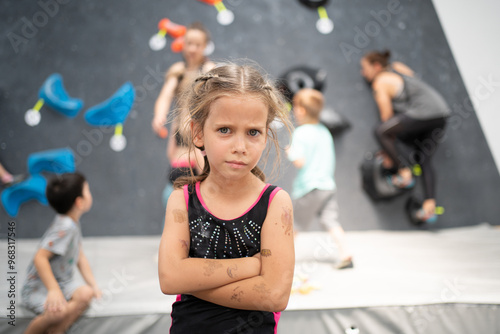 Fotografie Portrait of confident little girl climber standing arms crossed in sports center