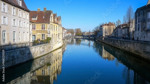 A view of a canal from a bridge, with the water reflecting the clear blue sky and surrounding architecture.