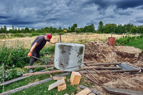 Method of roller system for moving cargo when installing septic tank made of concrete rings in rural areas. photo