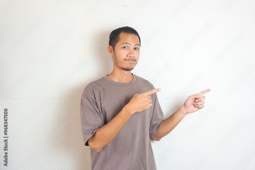 Young Adult Asian men pointing finger to the right with smiling face and exited expression with isolated white background
