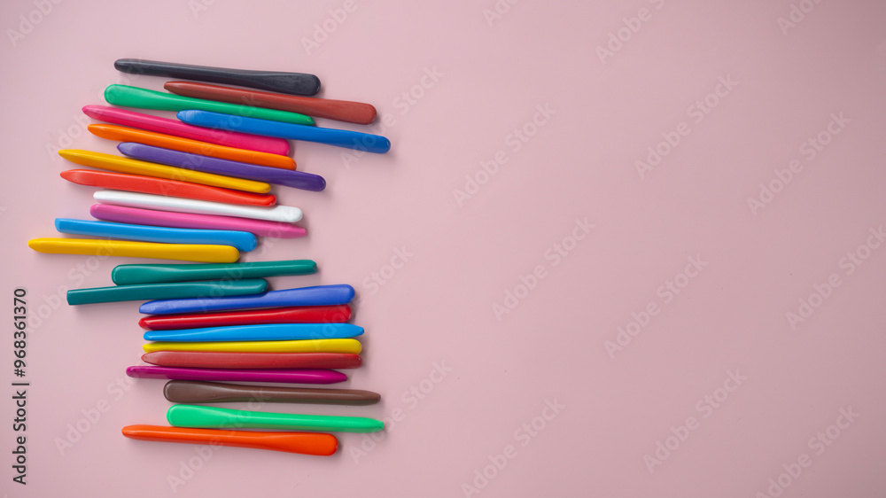 A row of colorful pencils are arranged on a pink background A row of colorful pencils are arranged on a pink background