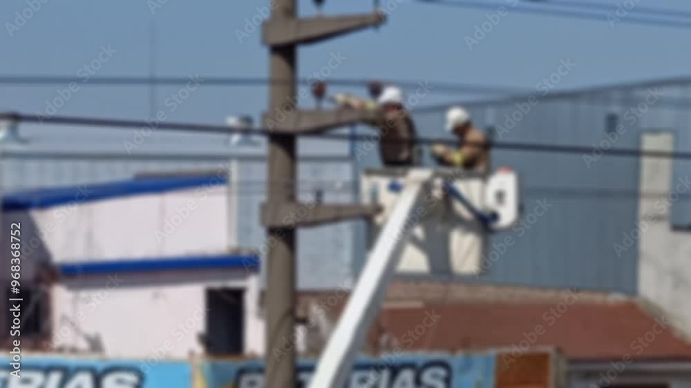 Intentionally out of focus electricians carrying out repairs on a light pole. electricity concept. Intentionally out of focus electricians carrying out repairs on a light pole. electricity concept.