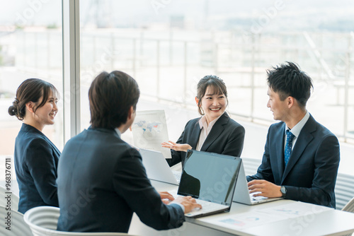 企業のオフィスで笑顔で会議・ミーティング・商談をするビジネスマン・ビジネスウーマン
