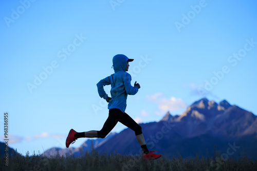 Fitness woman trail runner running on grassland mountain top