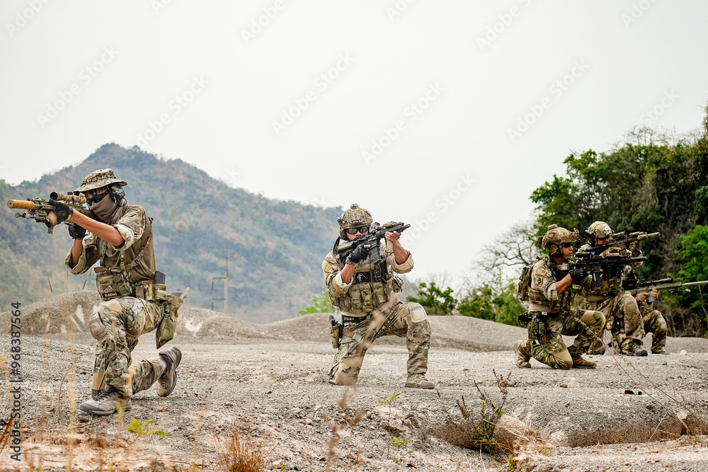 Fototapeta premium A group of military men in combat gear patrol in the middle of a desert and tropical jungle. Soldiers in full combat gear in dry weather conditions assemble and march on a mission.