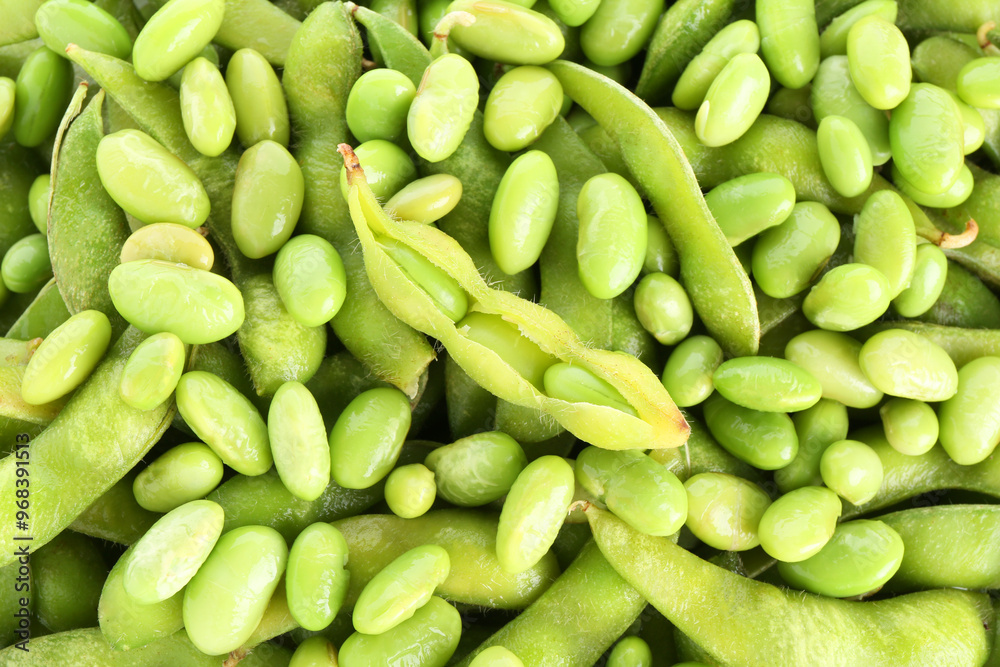 Raw green edamame pods on soybeans as background, closeup Raw green edamame pods on soybeans as background, closeup