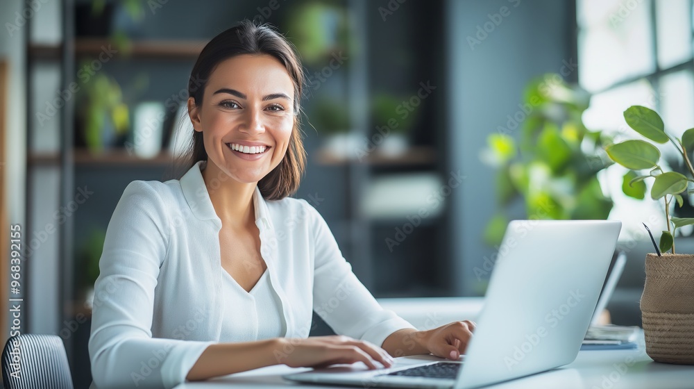 smiling businesswoman sitting at her desk with a laptop