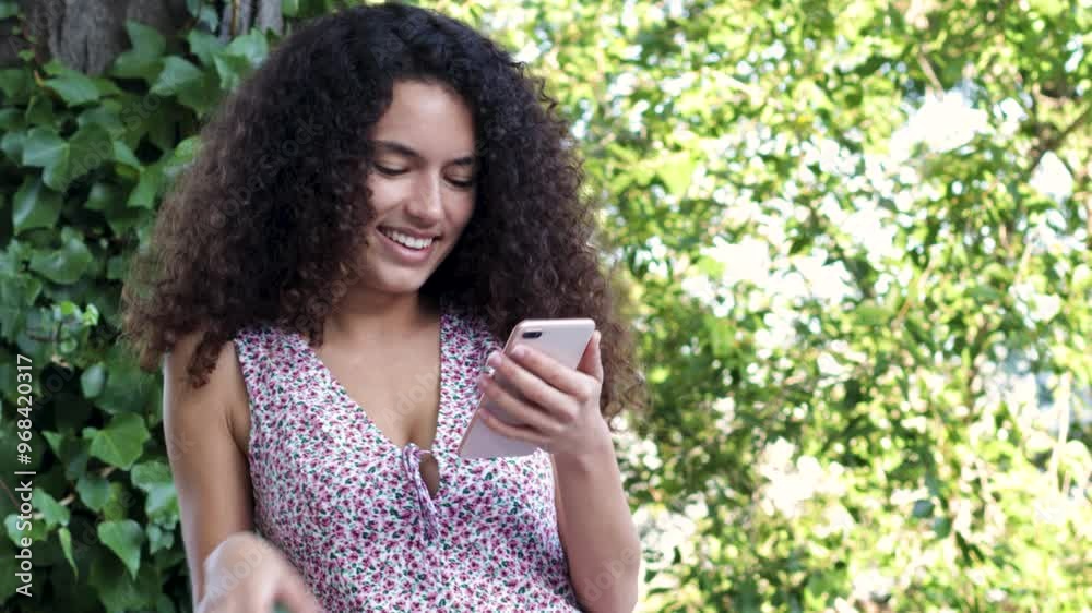 African-American girl using a smartphone in the park on a summer day. African-American girl using a smartphone in the park on a summer day.