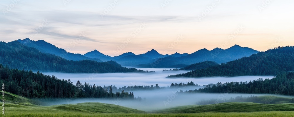 Fototapeta premium A breathtaking landscape showcasing mountains and a tranquil misty valley at dawn, perfect for nature enthusiasts.
