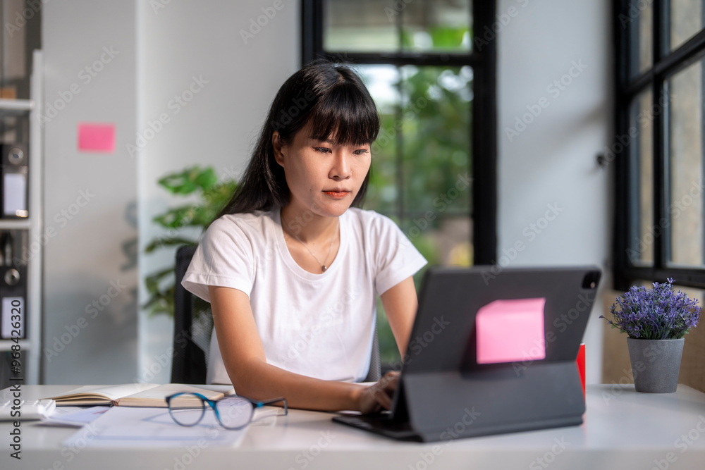 Young asian woman using tablet computer working from home