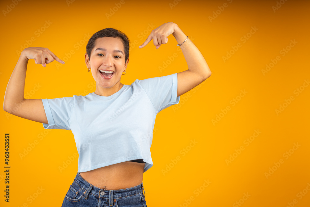 Young woman pointing herself with positive expression on yellow background Young woman pointing herself with positive expression on yellow background