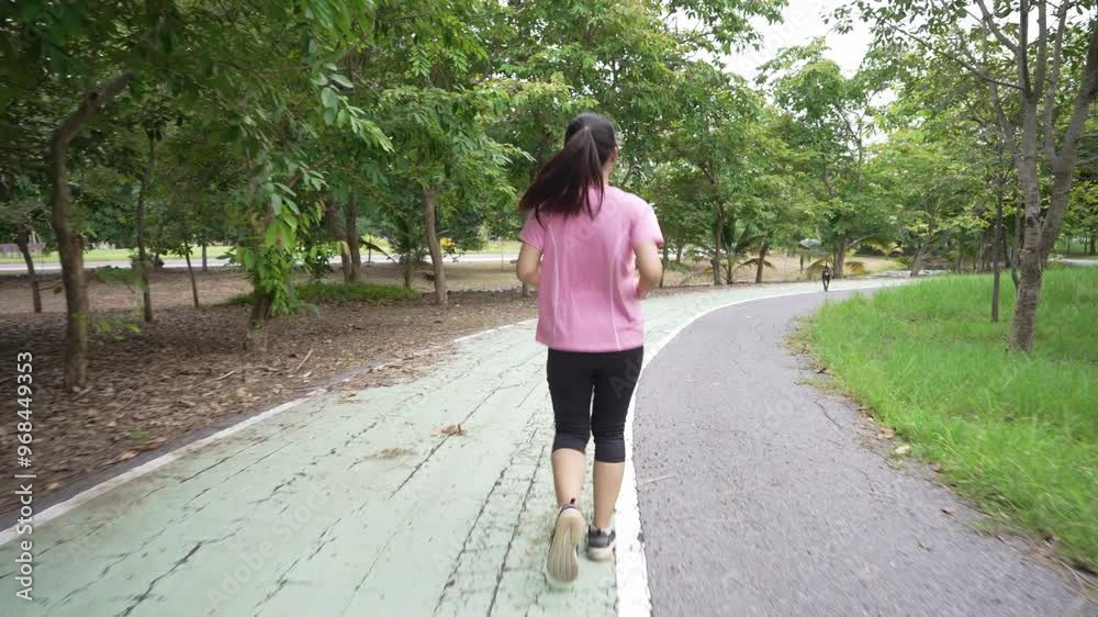 A rear view of a young Asian woman jogging for exercise on a park road, wearing athletic attire and embracing a healthy lifestyle A rear view of a young Asian woman jogging for exercise on a park road, wearing athletic attire and embracing a healthy lifestyle