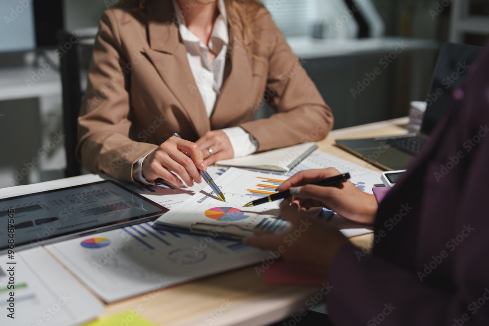 Two businesswomen are sitting at a table in a conference room, talking, discussing, meeting, financial business information. Online marketing, information, documents, laptop in modern office. Two businesswomen are sitting at a table in a conference room, talking, discussing, meeting, financial business information. Online marketing, information, documents, laptop in modern office.