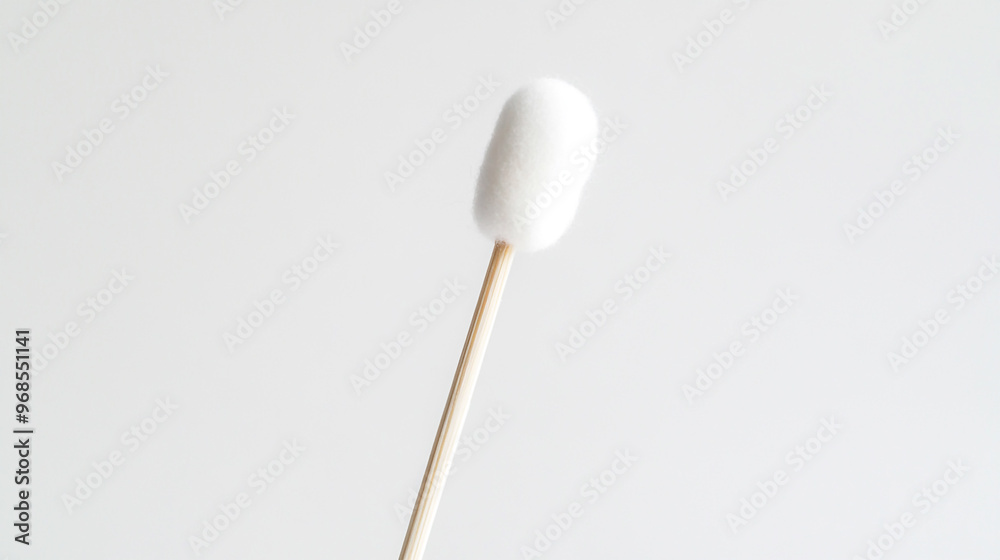 Close-up of a single cotton swab held against a plain white background, highlighting the soft tip and wooden stick during a clean-up routine Close-up of a single cotton swab held against a plain white background, highlighting the soft tip and wooden stick during a clean-up routine