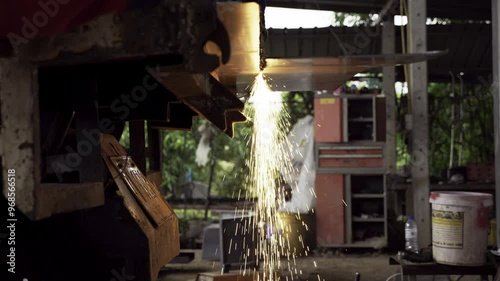 Flying sparks of fire coming from a metal being cut inside a local machine shopper using an electronic cutter. photo