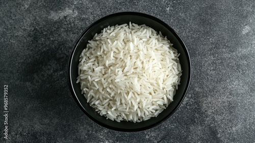 Minimalist image of white rice in a black bowl, top view on a grey background, emphasizing clean design and presentation.