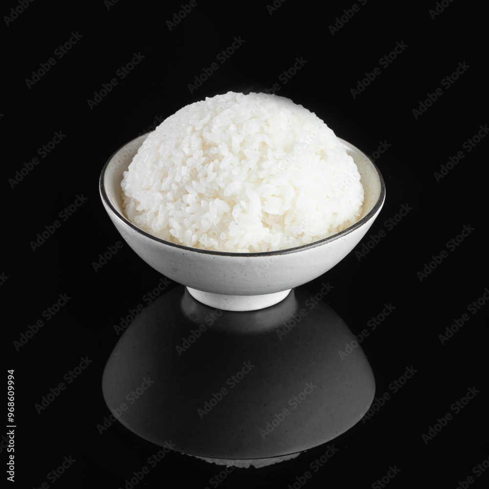 A bowl of perfectly cooked white rice against a dark background, showcasing a minimalist and elegant food presentation. A bowl of perfectly cooked white rice against a dark background, showcasing a minimalist and elegant food presentation.