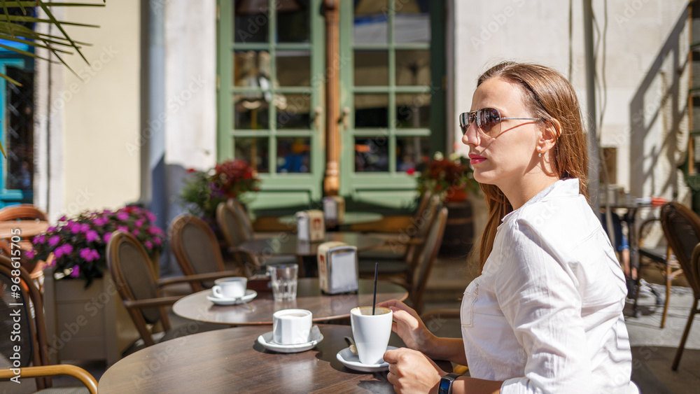 Woman enjoying coffee at an outdoor cafe on a sunny afternoon in the city Woman enjoying coffee at an outdoor cafe on a sunny afternoon in the city