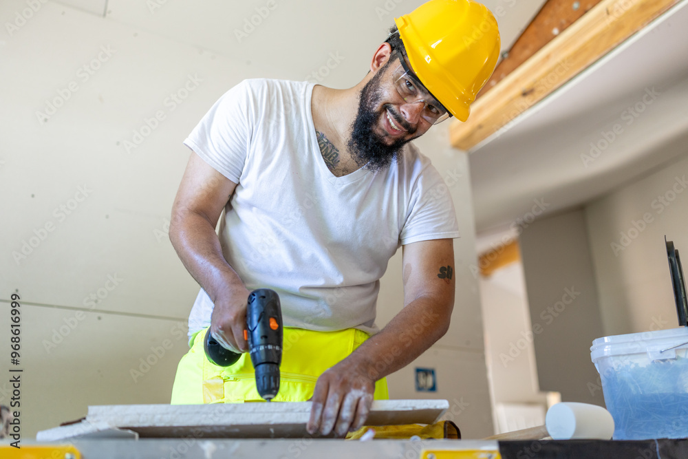 A dynamic male construction worker in a safety helmet and bright vest skillfully uses a powerful drill on a house remodeling project at a busy construction site, showcasing his expertise A dynamic male construction worker in a safety helmet and bright vest skillfully uses a powerful drill on a house remodeling project at a busy construction site, showcasing his expertise