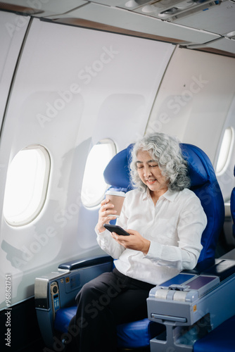  Asian seniorexecutive excels in first class, multitasking with digital tablet, laptop and smartphone. Travel in style, photo