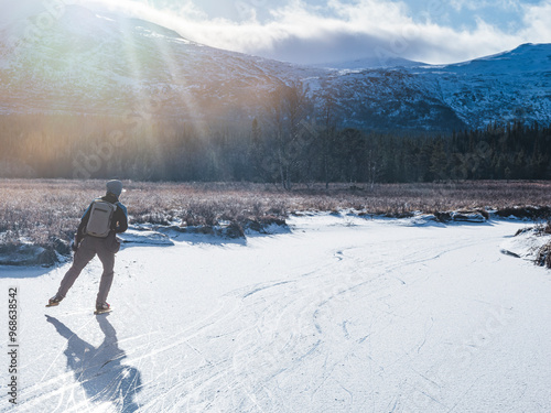 Full length of man ice skating on frozen lake during sunny day