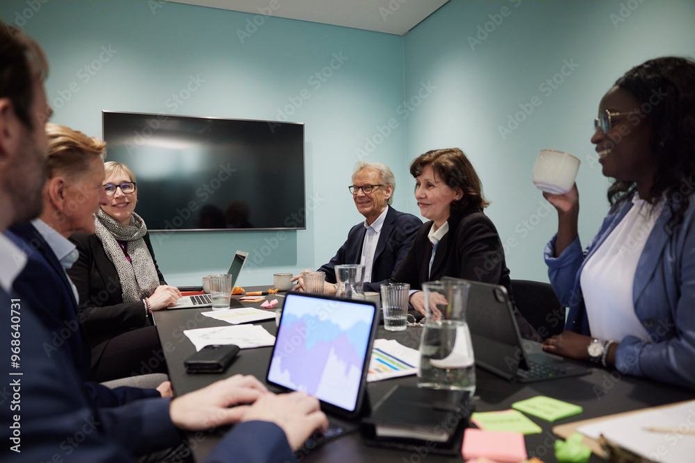 Multiracial corporate colleagues working over conference table in office Multiracial corporate colleagues working over conference table in office