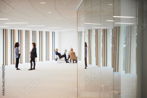 Multiracial businesswomen discussing ideas while coworkers sitting in office lobby