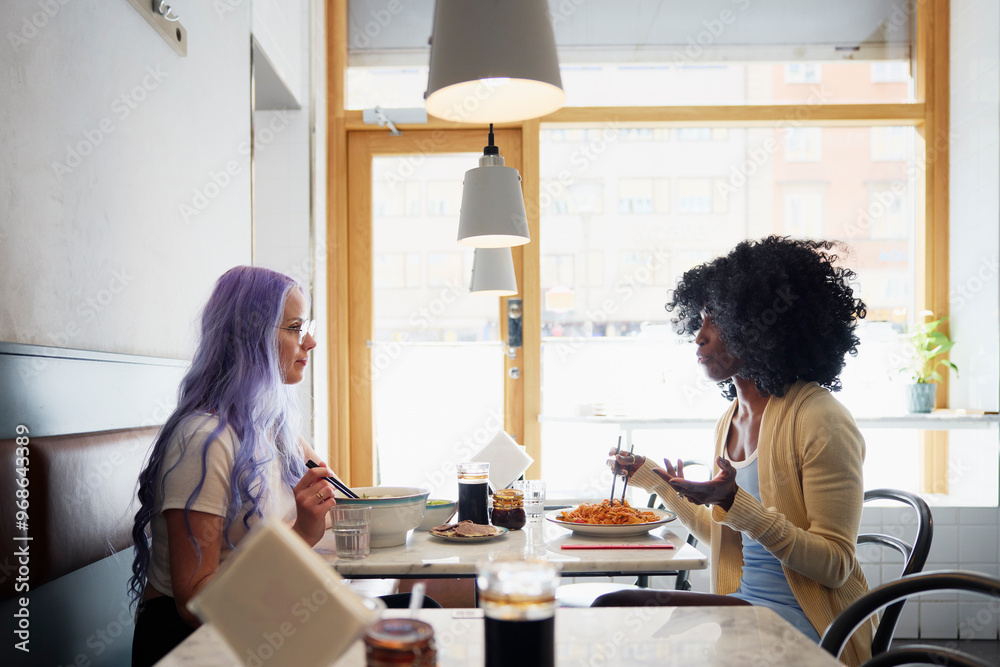 Multiracial female friends having food in cafe Multiracial female friends having food in cafe