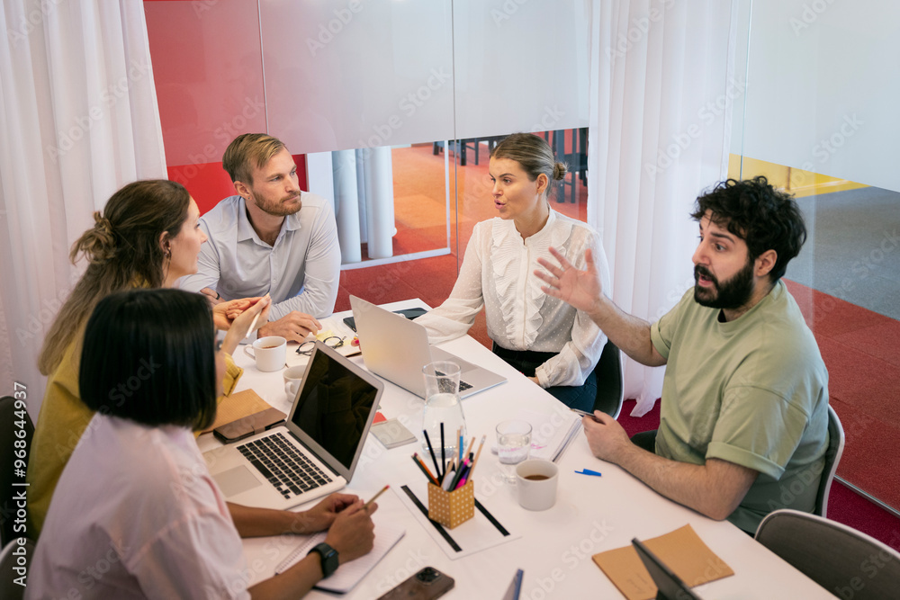 Corporate colleagues discussing new strategies while sitting over table in office Corporate colleagues discussing new strategies while sitting over table in office