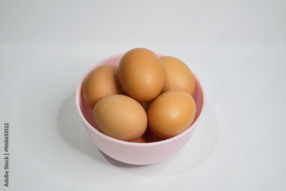 Close up of chicken eggs in the pink bowl isolated on white background