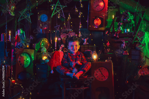 A happy boy-child is in the New Year decorations. A child in Christmas pajamas.