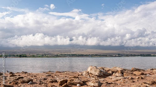 hyperlapse shot on the shore of Lake Issyk Kul, with an isoimage of the Tien Shan mountain range in the background, clouds moving over the mountains photo