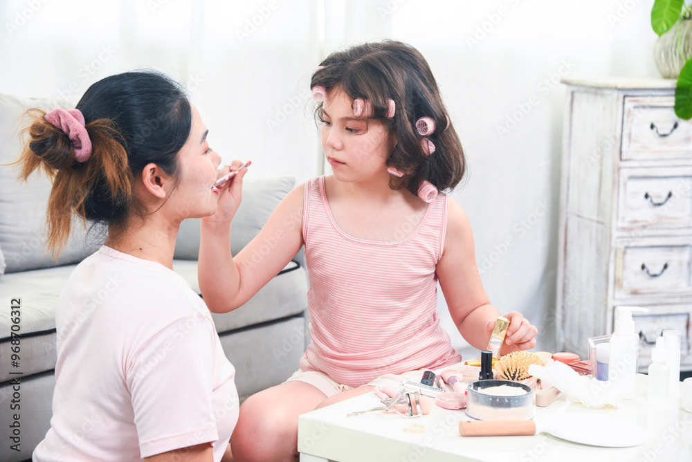 Fototapeta premium Mother teaches the child to do makeup. Mother and little daughter are doing makeup on each other and having fun.