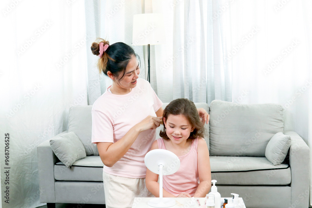 Happy family, loving Asia mom comb daughter's hair in living room at home. Mother doing hairstyles. Having fun together. Happy family, loving Asia mom comb daughter's hair in living room at home. Mother doing hairstyles. Having fun together.