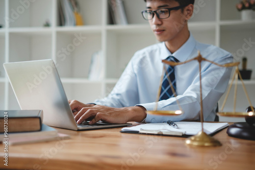 Lawyer Working on Laptop with Scales of Justice in Office