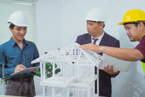 A male engineer and contractor at a desk in an office discuss the structural design of a house,roof drafting, lot size and number of occupants for a dream home project,focusing on budget and style