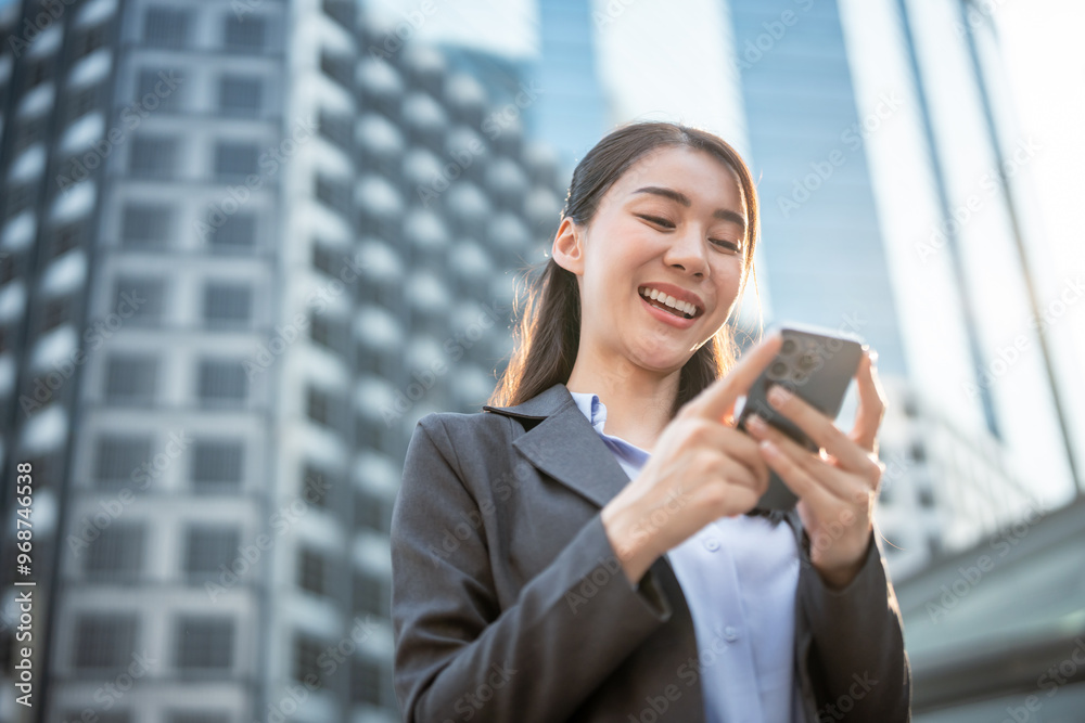 Asian young businesswoman using smartphone while standing in the city. Asian young businesswoman using smartphone while standing in the city.