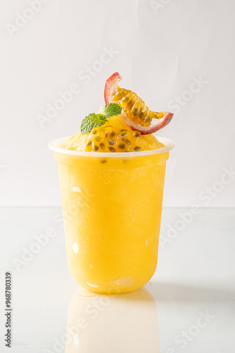 Refreshing chilled passion fruit drink in a plastic cup, garnished with fresh mint and passion fruit slice. Ideal for summer refreshment. photo