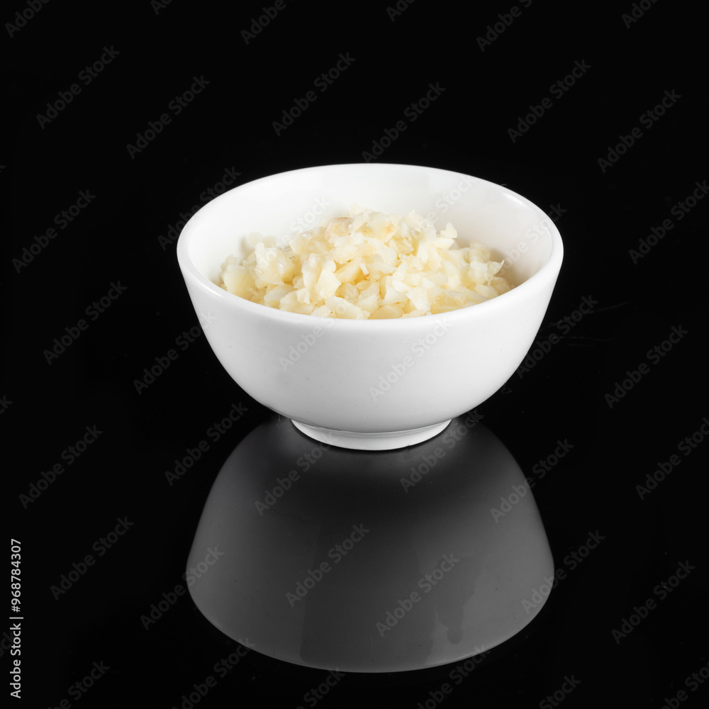 White rice served in a plain white bowl on a sleek black surface, capturing minimalist food presentation.