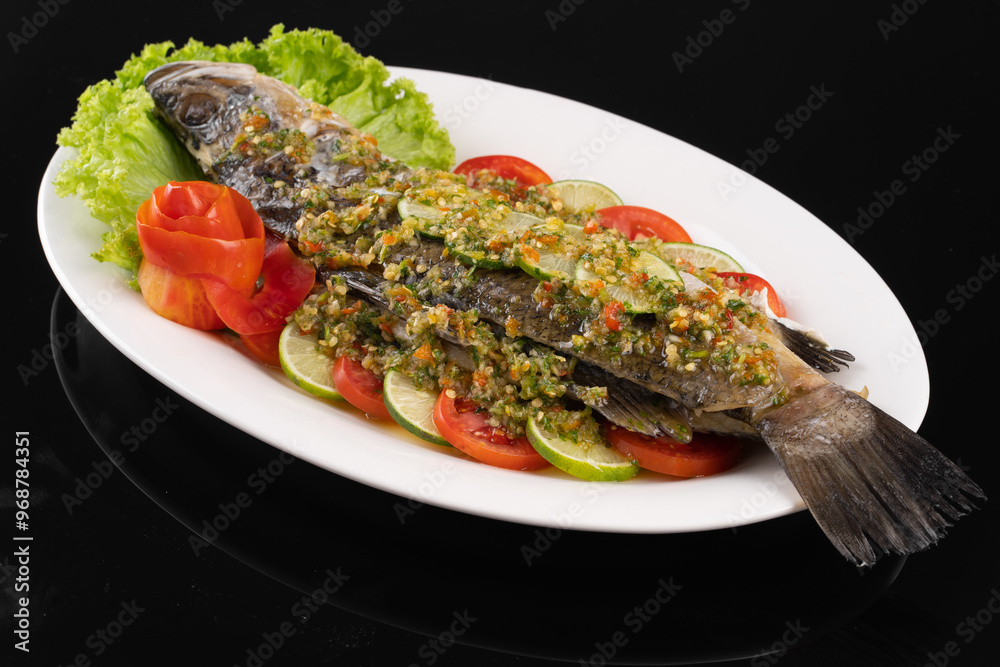 Whole fish garnished with sauce and fresh vegetables on a white plate. Perfect for seafood lovers and culinary presentations. Whole fish garnished with sauce and fresh vegetables on a white plate. Perfect for seafood lovers and culinary presentations.