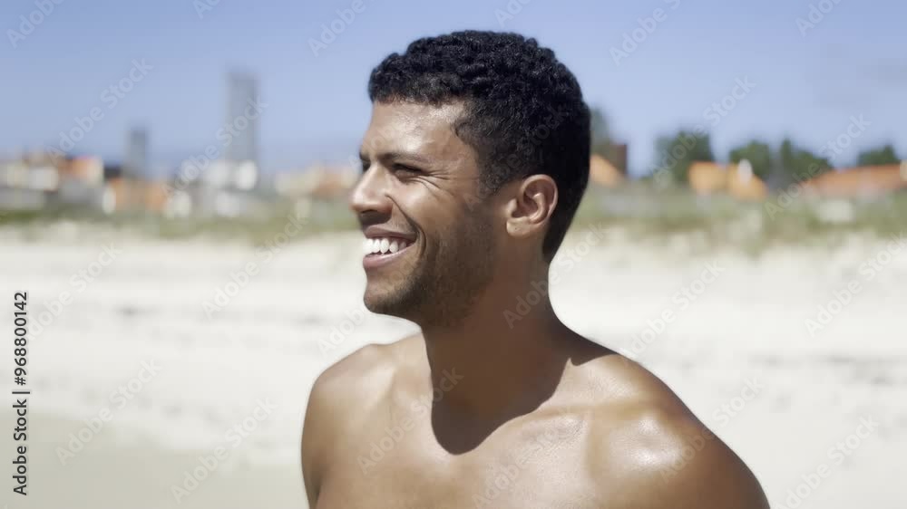 A joyful Black man smiles warmly at the camera while standing on a sunny urban beach in Galicia, Spain. The vibrant cityscape and serene ocean create a perfect mix of urban and natural beauty. A joyful Black man smiles warmly at the camera while standing on a sunny urban beach in Galicia, Spain. The vibrant cityscape and serene ocean create a perfect mix of urban and natural beauty.